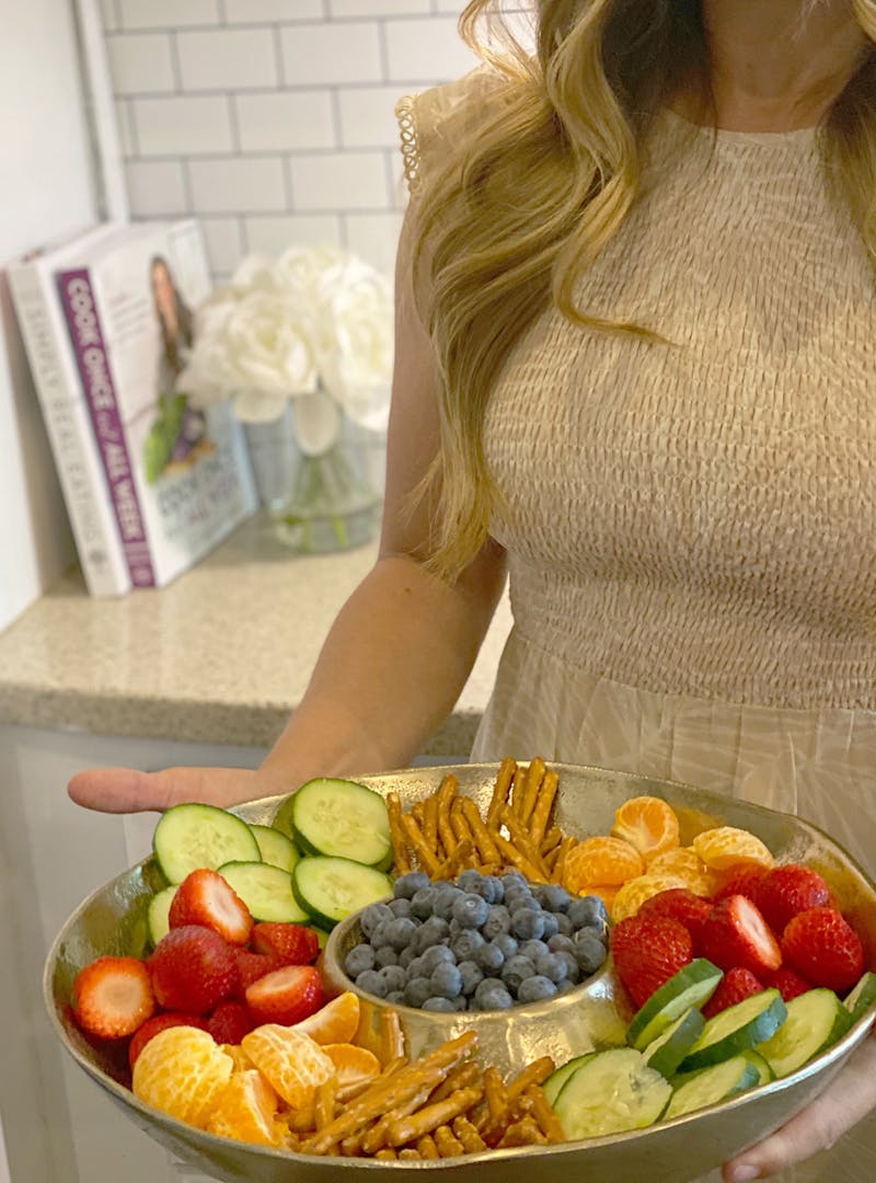 A tray of healthy bedtime snacks, including oranges, strawberries, cucumbers and pretzels.