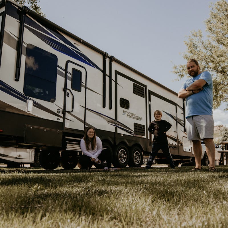 A family standing outside their Toy Hauler RV in the grass.