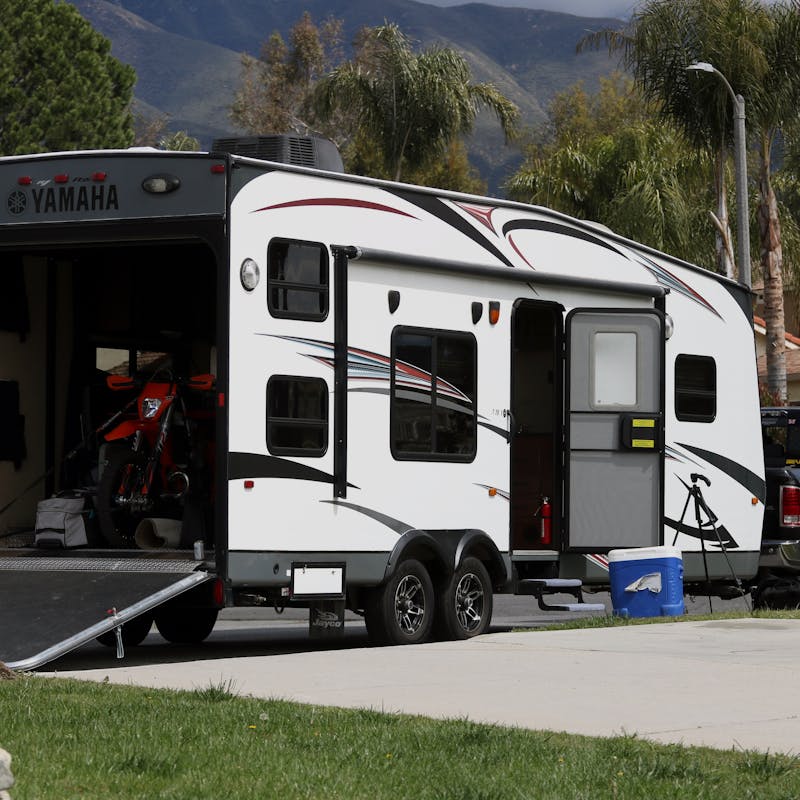 A toy hauler parked on the street with a dirt bike loaded into the back.