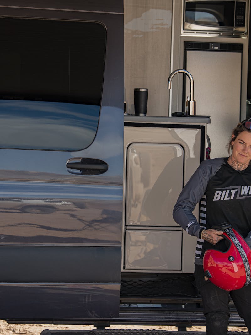 Kalen Thorien holding her dirt bike helmet in front of the thor motor coach sanctuary 