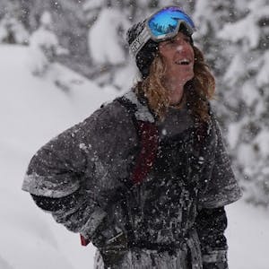 Ryan Barrick stands in snow with goggles, looking up at white sky