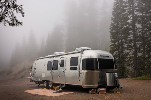 Karen and Lenny Blue's Airstream Flying Cloud travel trailer parked at a campsite in the foggy woods.
