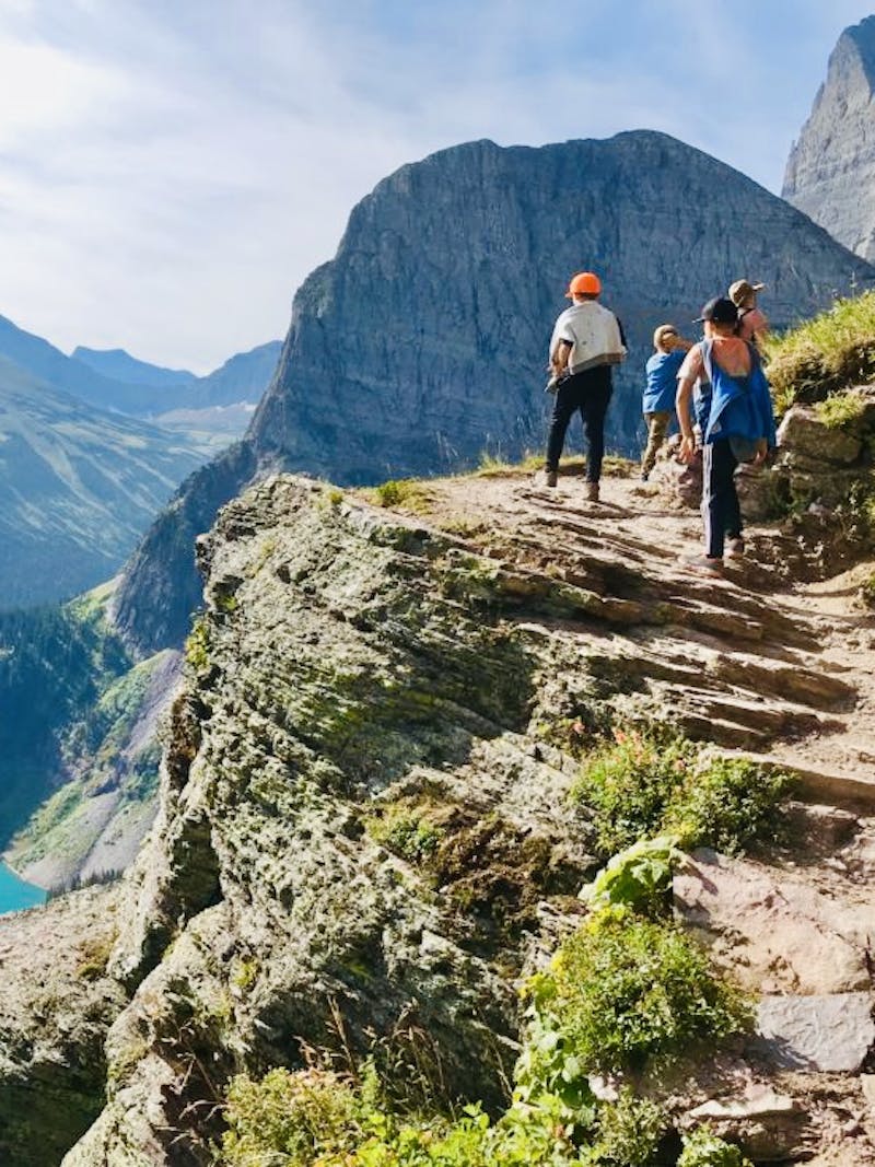 A family hiking a rocky path in idyllic Glacier National Park.