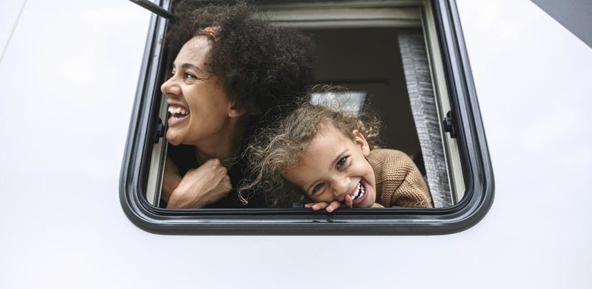 Mother and daughter laughing and smiling putting heads out of rv window