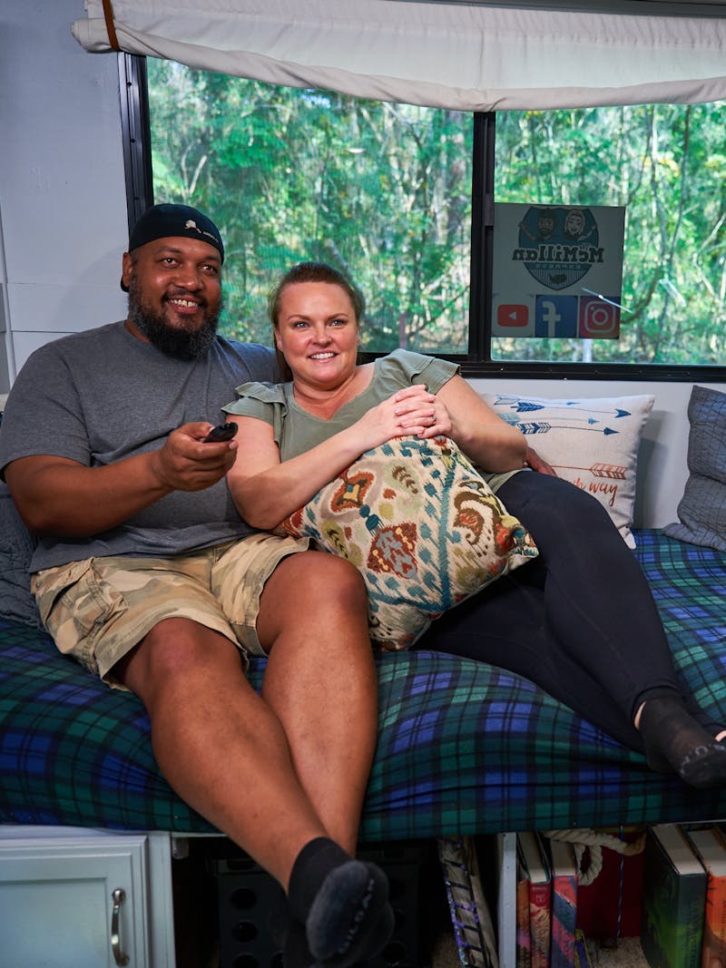 Ben and Christina McMillan lounging inside their RV watching TV