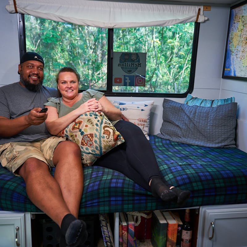 Ben and Christina McMillan lounging inside their RV watching TV