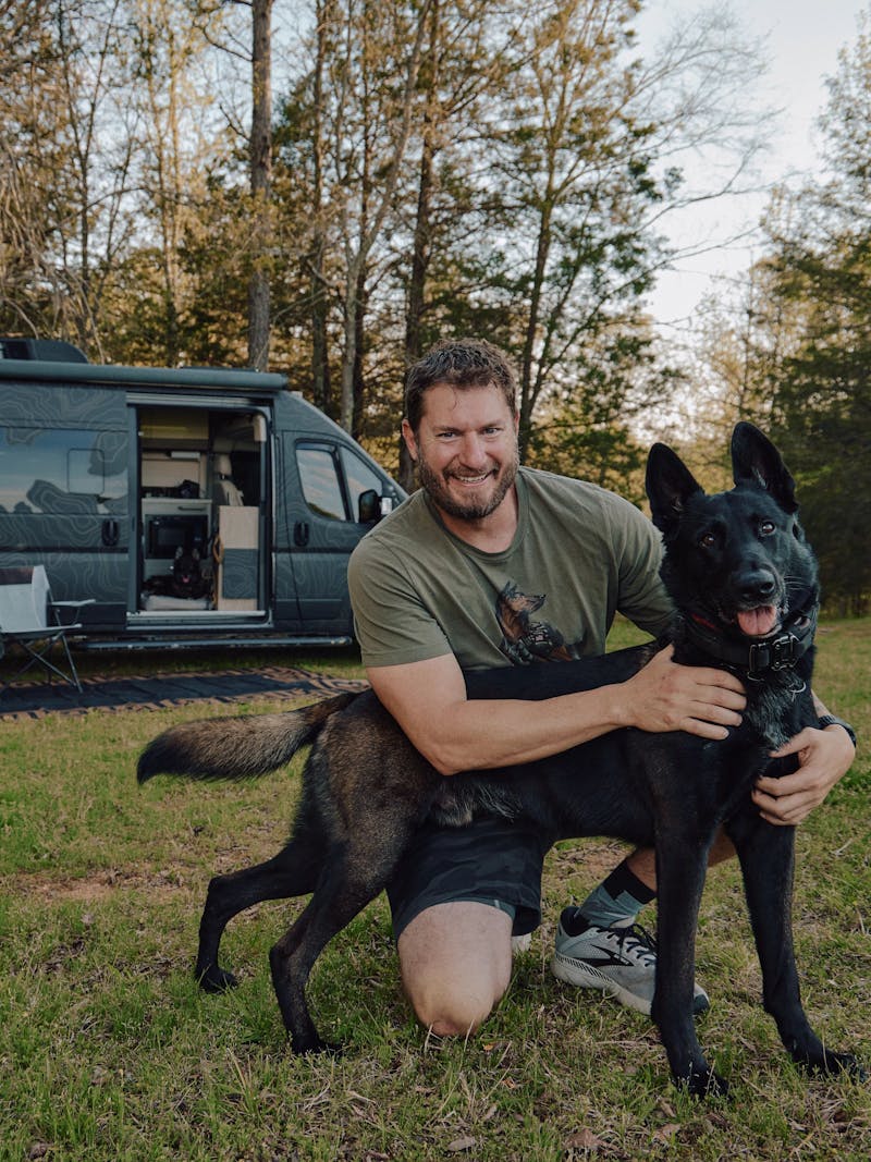 Aaron Tucker holds his dog in front of his van