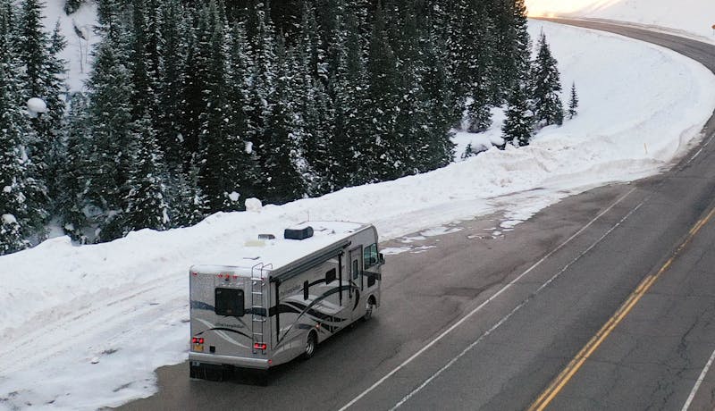 An RV driving up a mountain in golden light.