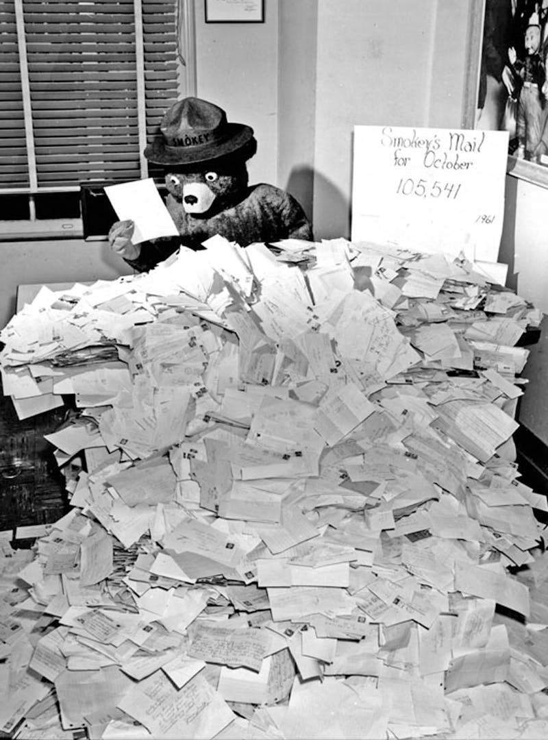 Black and white photo of Smokey Bear reading fan mail