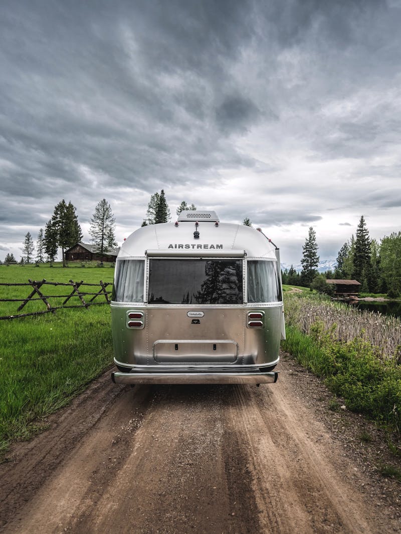 The back of an Airstream travel trailer driving down a dirt road