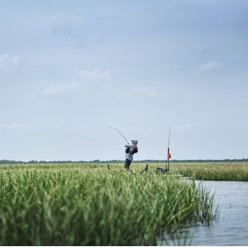 Robert Field stands on his kayak while fishing.