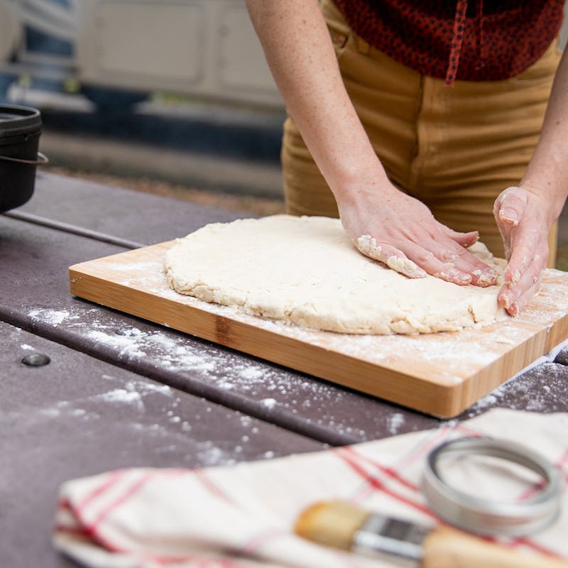 Patting biscuit dough into a uniform thickness.