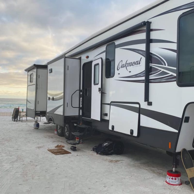 An RV trailer parked on the beach.