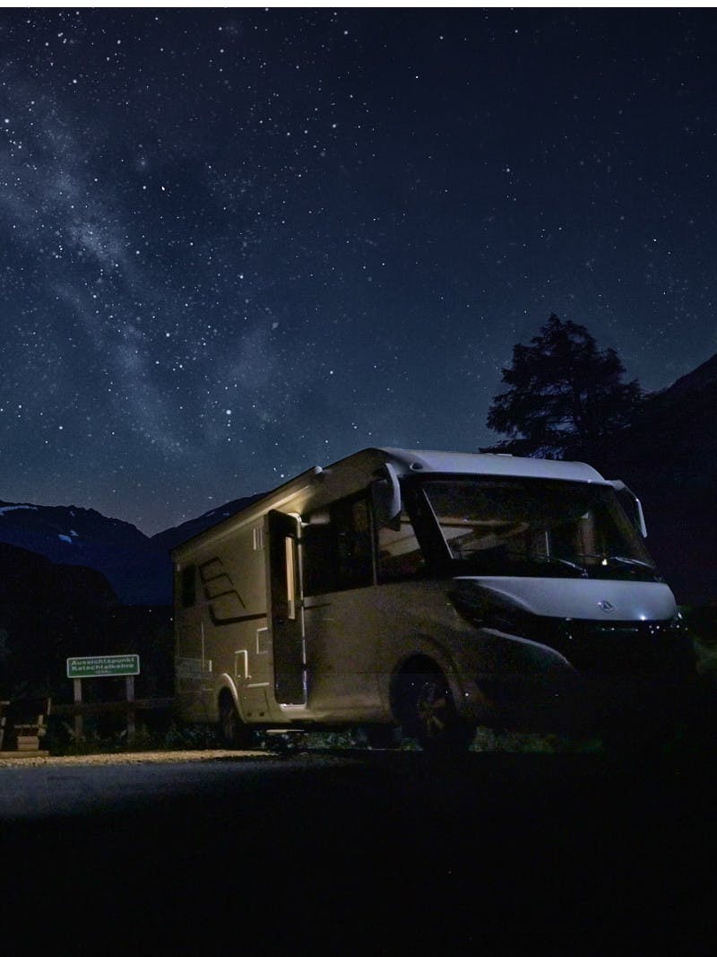 Family stargazes in the mountains of Austria next to their Class B RV from Hymer.