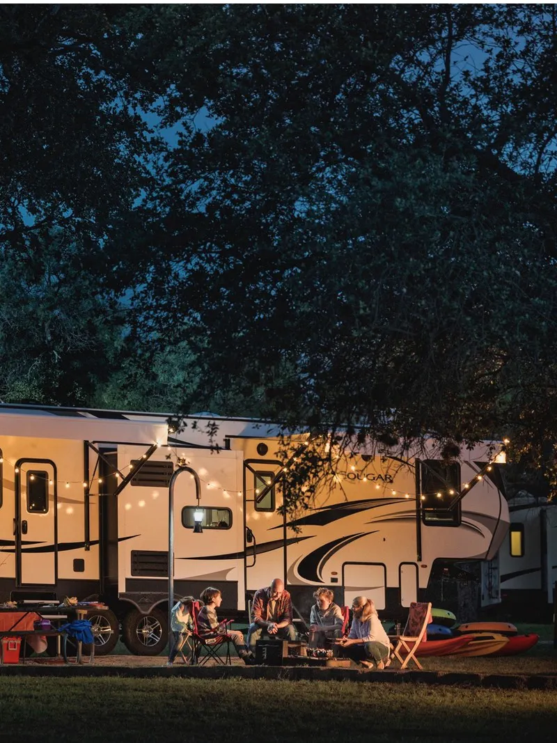 Family around campfire, in front of Keystone Cougar fifth wheel. 