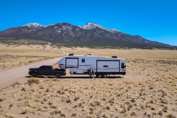 Bailey and Nicole Damberg pose in front of their Dutchmen Astoria Fifth Wheel in the desert.