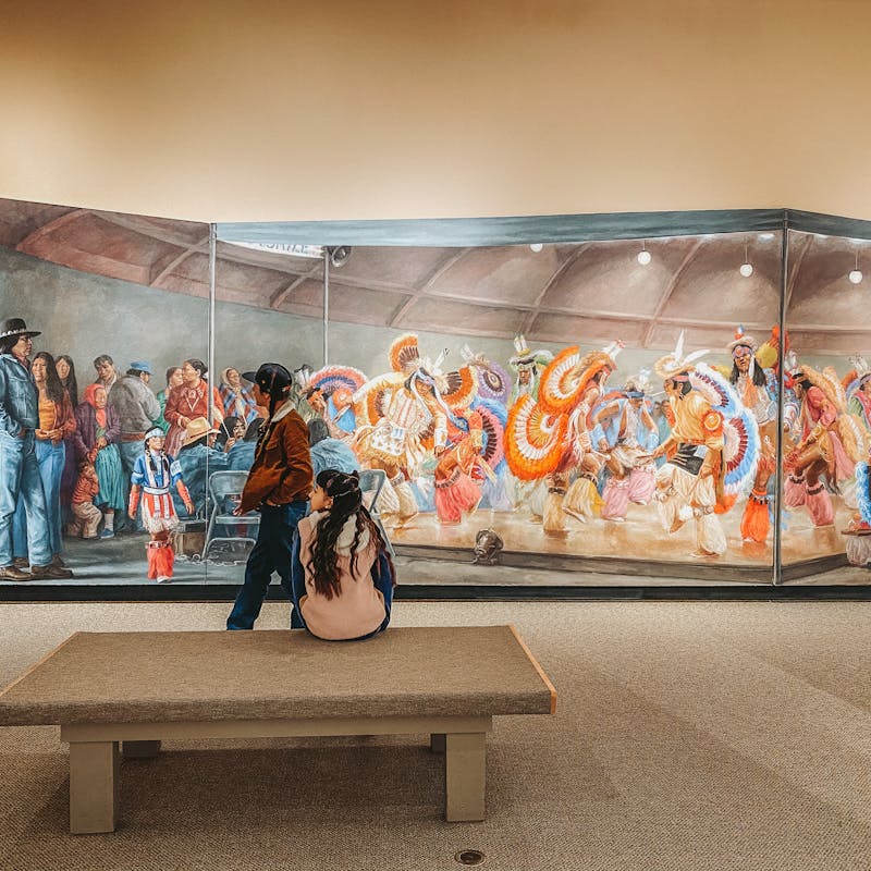 A wide shot of a museum mural depicting Native Americans in traditional and modern dress.
