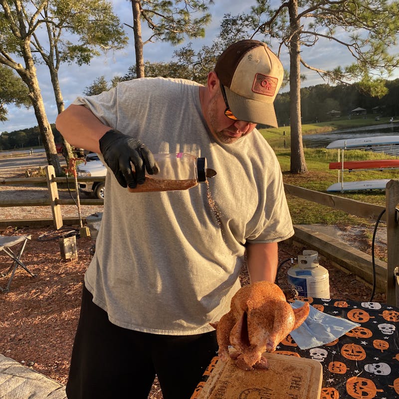 Abby Booth's husband sprinkles on a homemade seasoning blend onto a chicken.