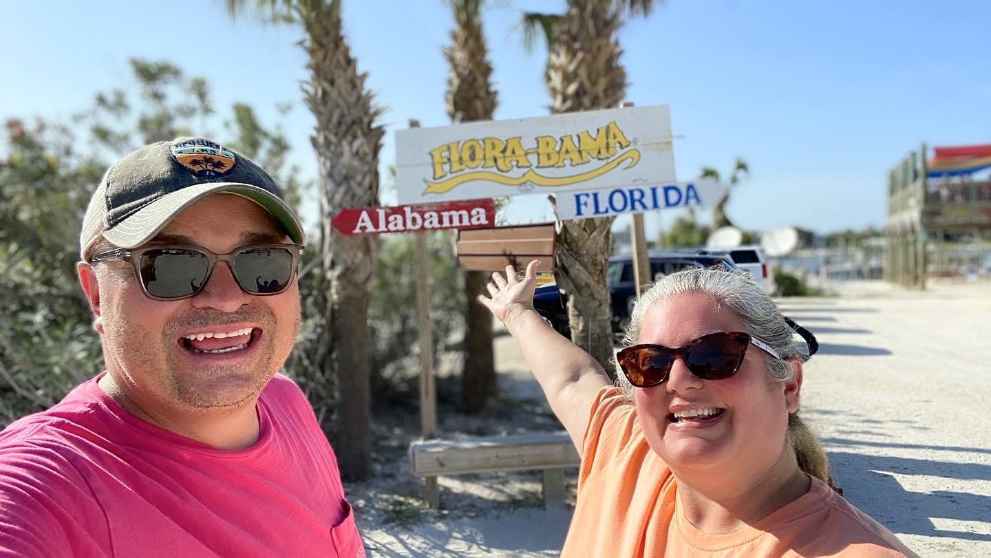 Micheal and Tiffany Dunagan smiling next to the flora-bama sign
