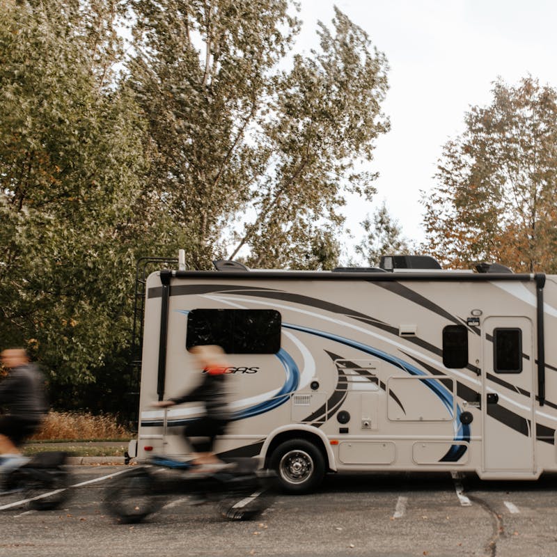 Dave and Kathy riding bikes in a whir past their parked RV.