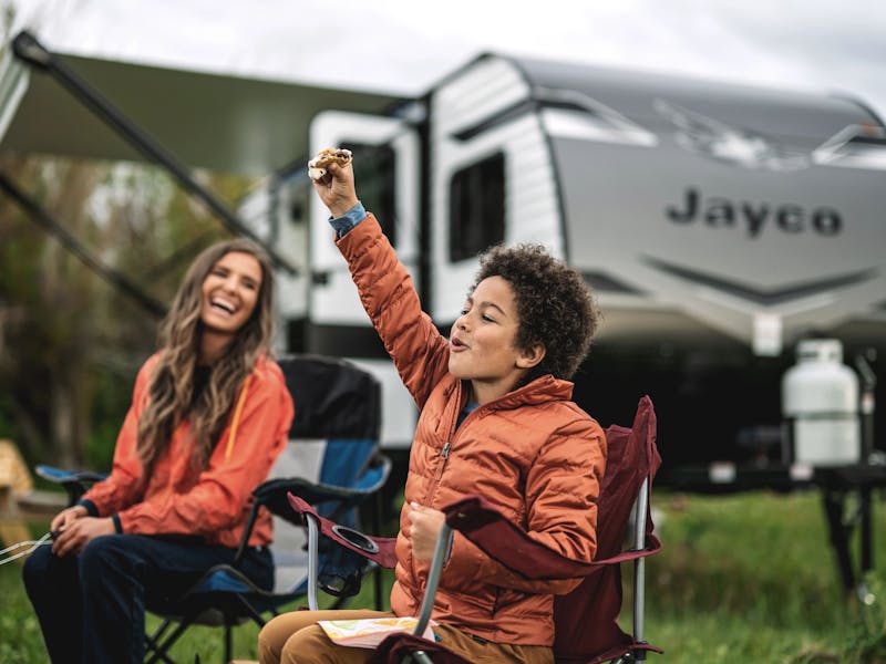 kid holding a smore in front of a jayco travel trailer