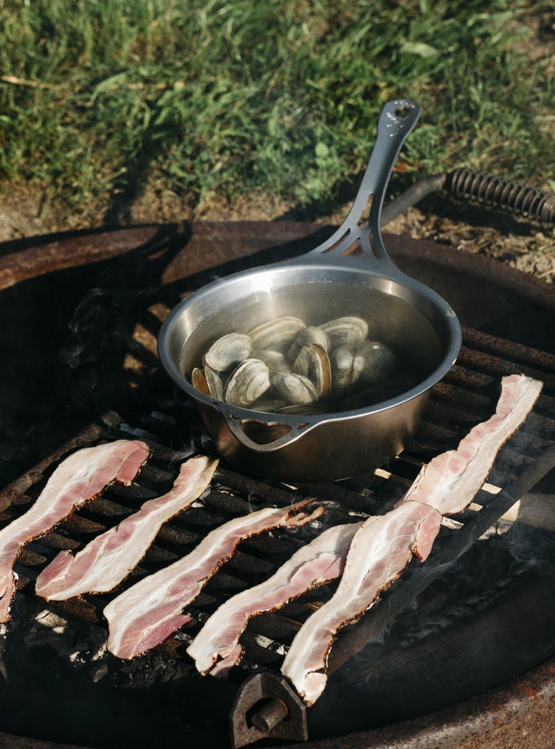 Bacon and clams cooking on a grill.