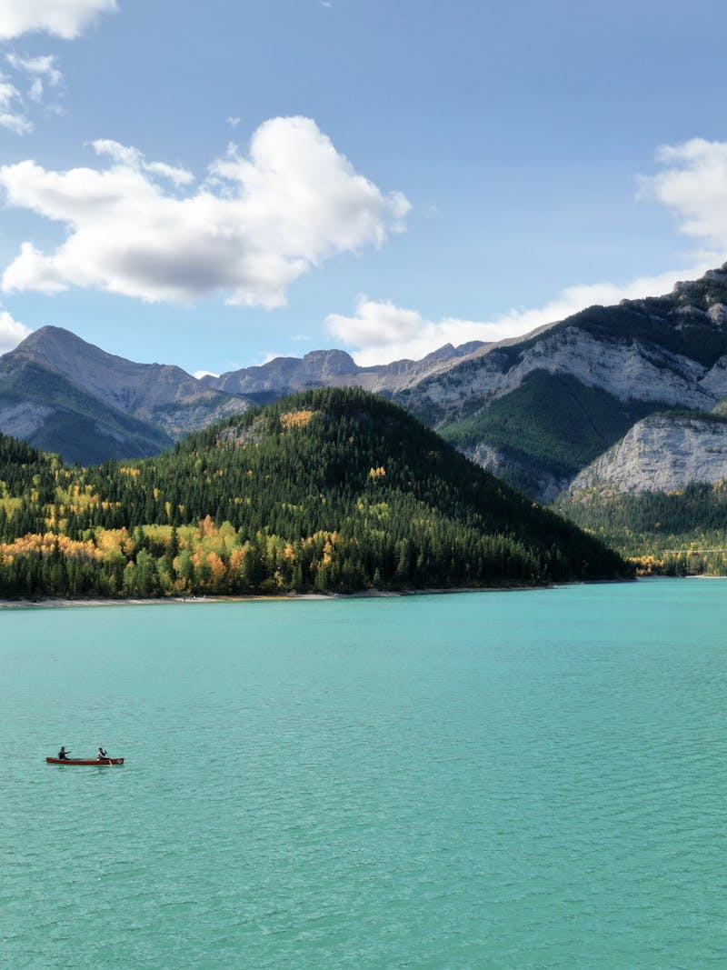 A couple kayaking on a pretty blue lake with mountains in the background. 