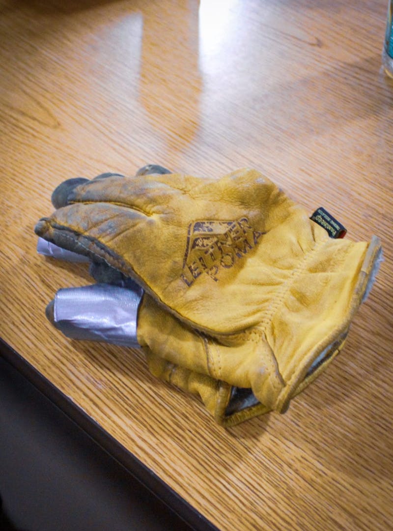 Worn yellow work gloves with duct tape
