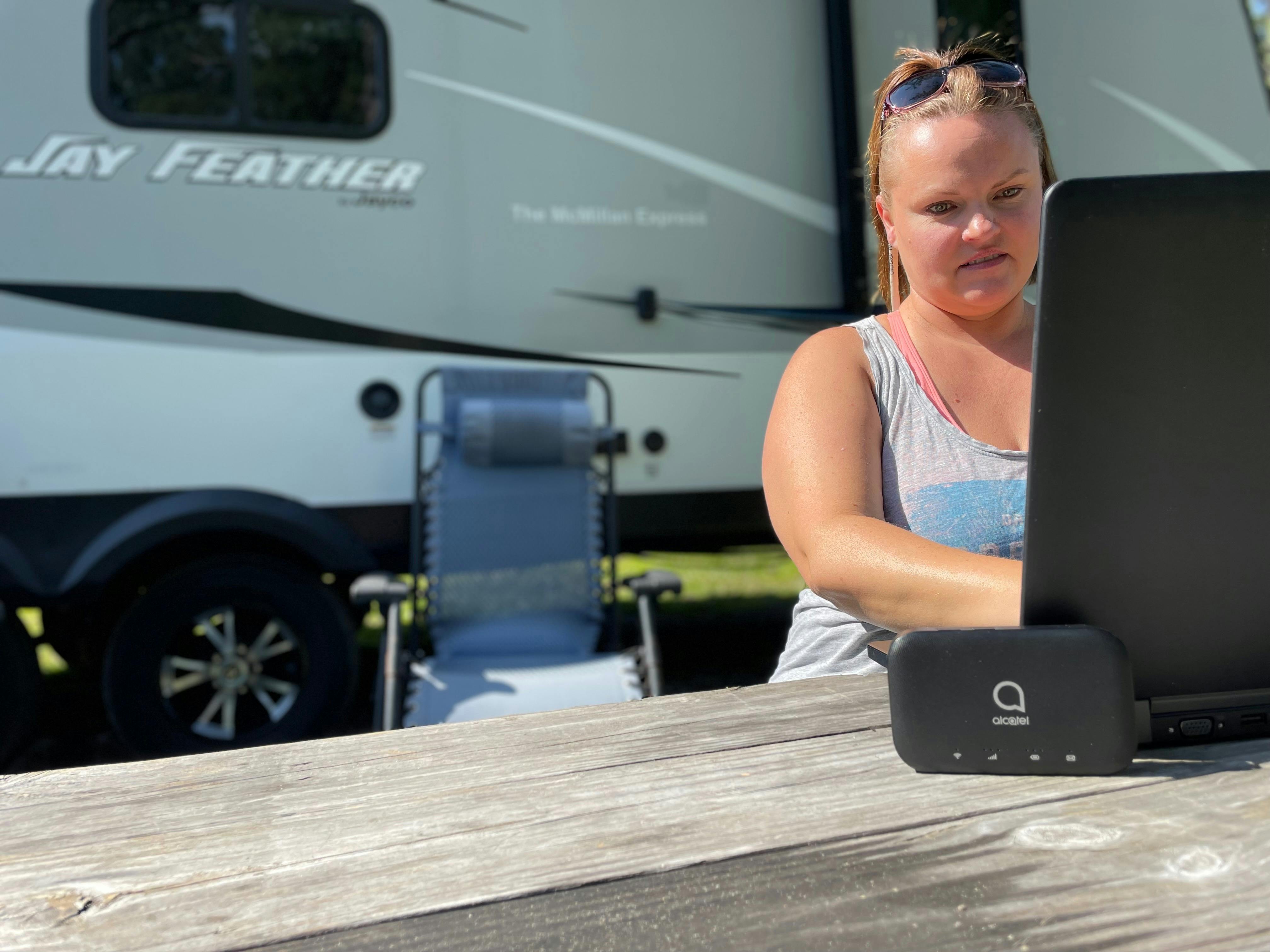 Christina McMillan using a cricket hot spot while on a laptop outside of her RV