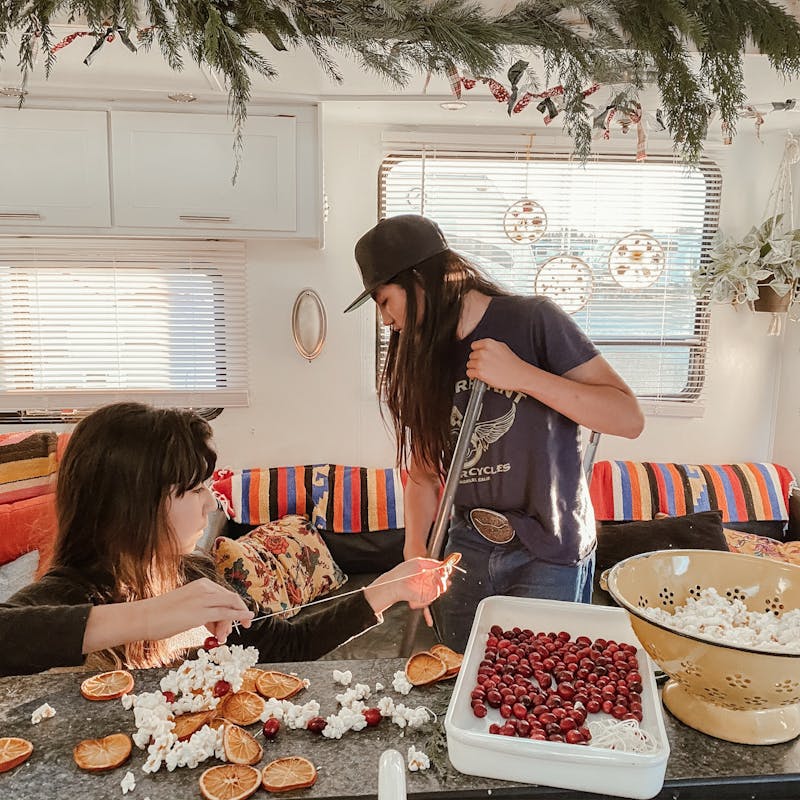 Two kids making Christmas garlands in an RV.