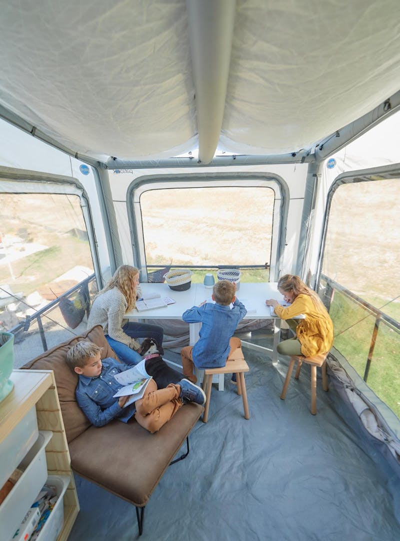 Brittnee Proha's children homeschooling in their Heartland Cyclone's patio tent.