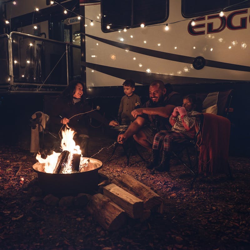 The Class Family gathered around a fire pit at night together.