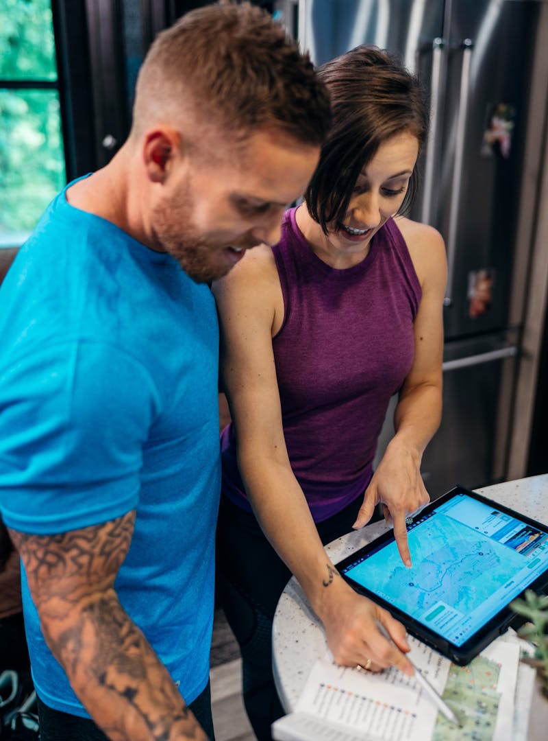 A man and a woman looking at an iPad and a map inside their RV.