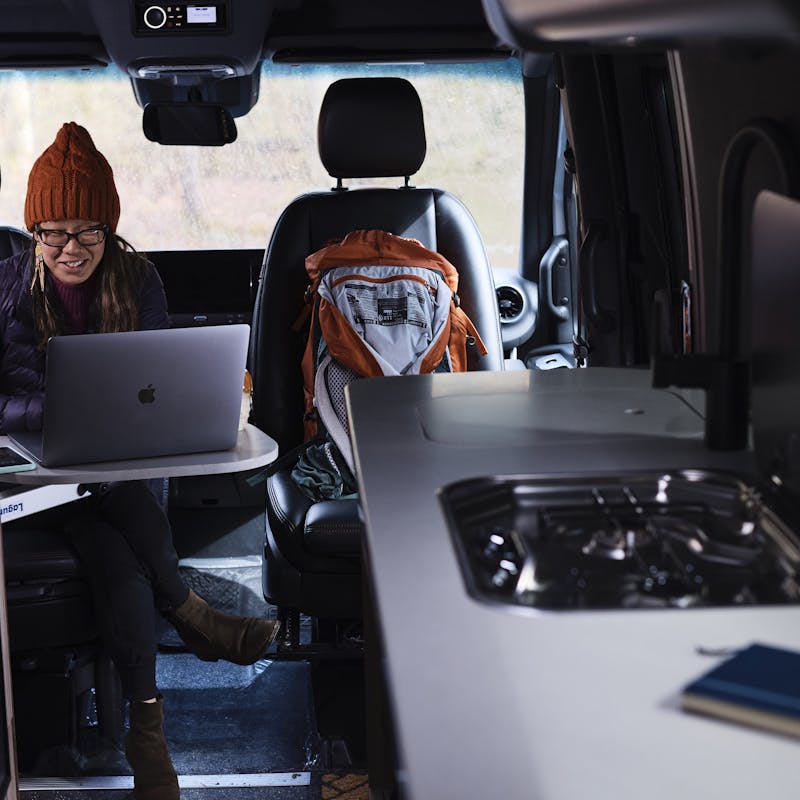 Kathy Karlo working on a laptop inside of an Airstream camper van