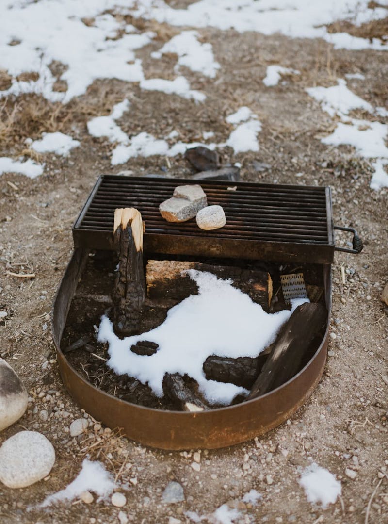 Close up of campsite fire pit with wood and snow