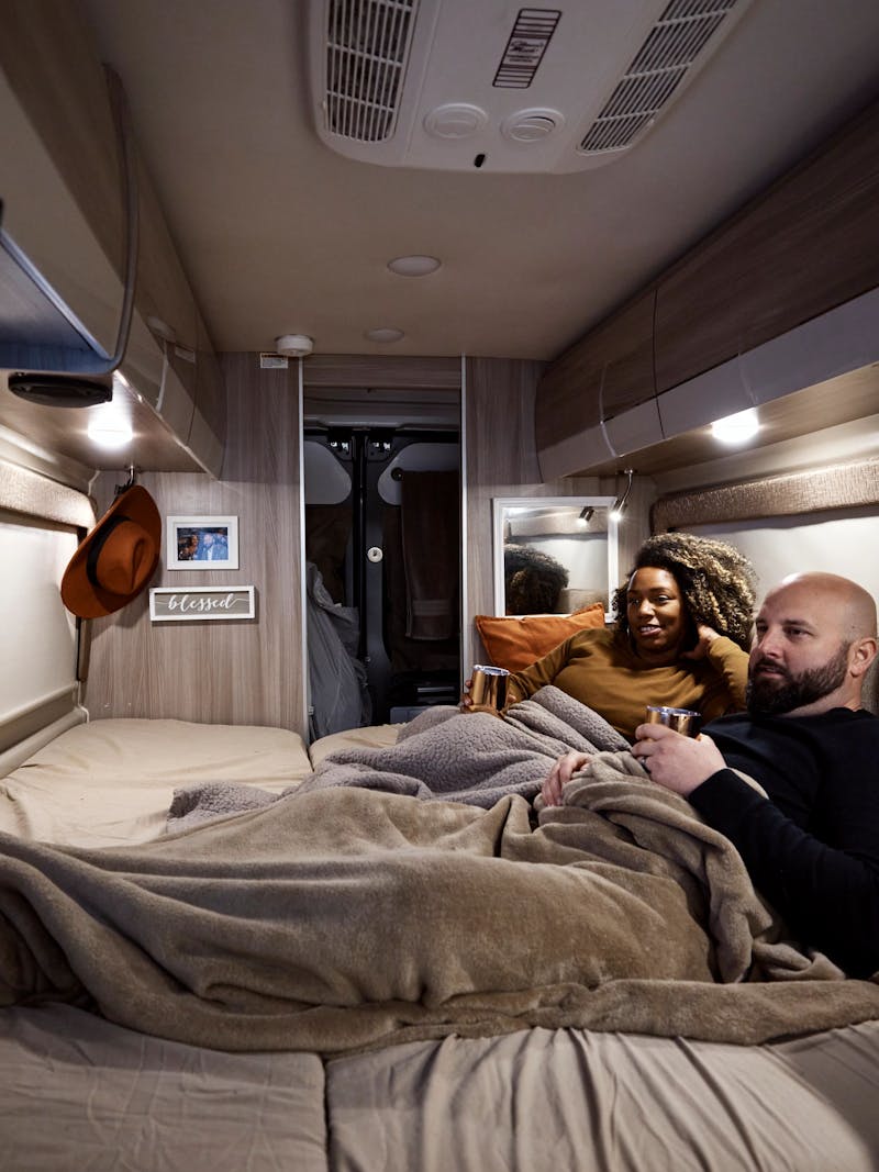 Gabe and Rocio Rivero lounge in the bed of their RV while they watch tv