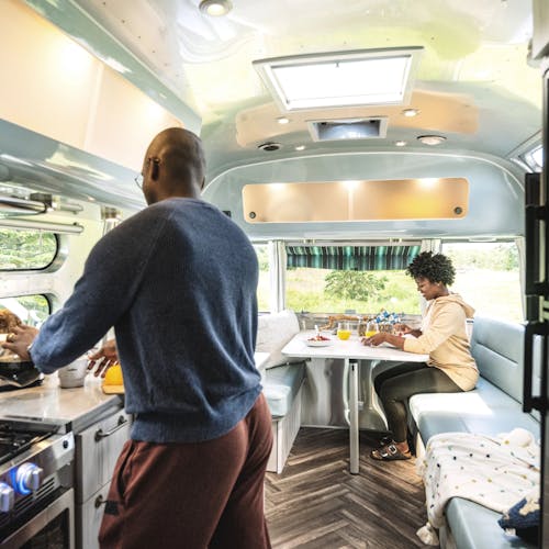 A couple relaxes in the kitchen and dinette are of an Airstream travel trailer