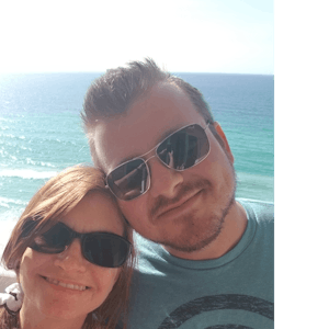 Julie and Brandon taking a selfie in front of the ocean wearing sunglasses.