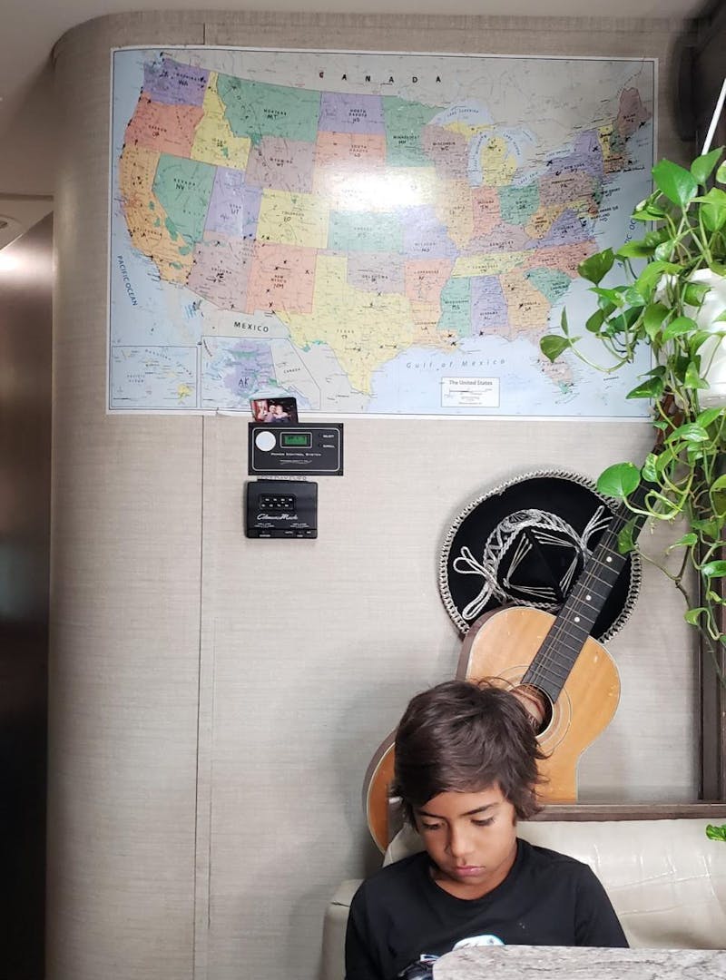 A map hangs on the wall inside of Sandra Peña's Class C RV near the kitchen table where her son sits.