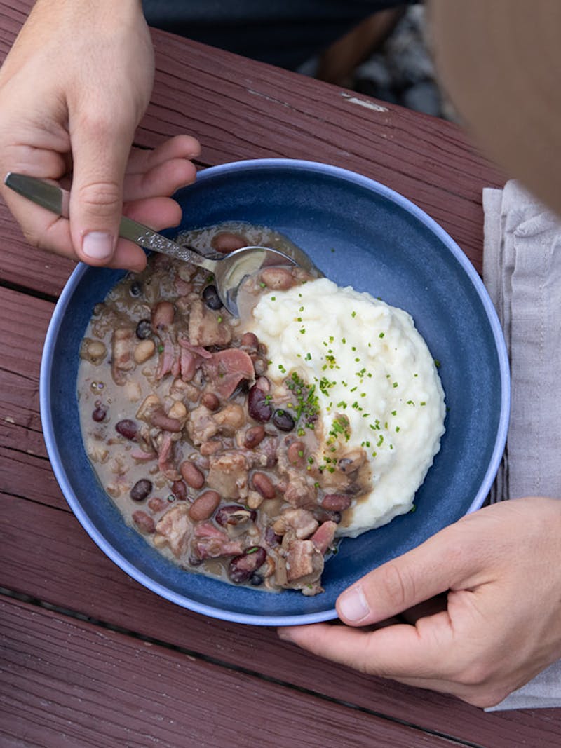 A bowl piled high with mashed potatoes and a medley of mixed beans. 