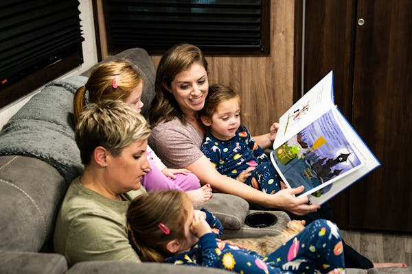 Moms reading to their triplet girls at night.