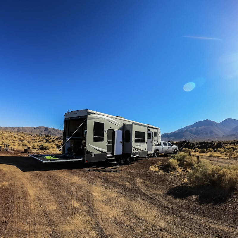 A toy hauler RV parked in the desert under a deep blue sky.
