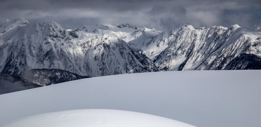 Snowy hill and snowy peaks at Revelstoke Mountain Resort in Revelstoke, BC.