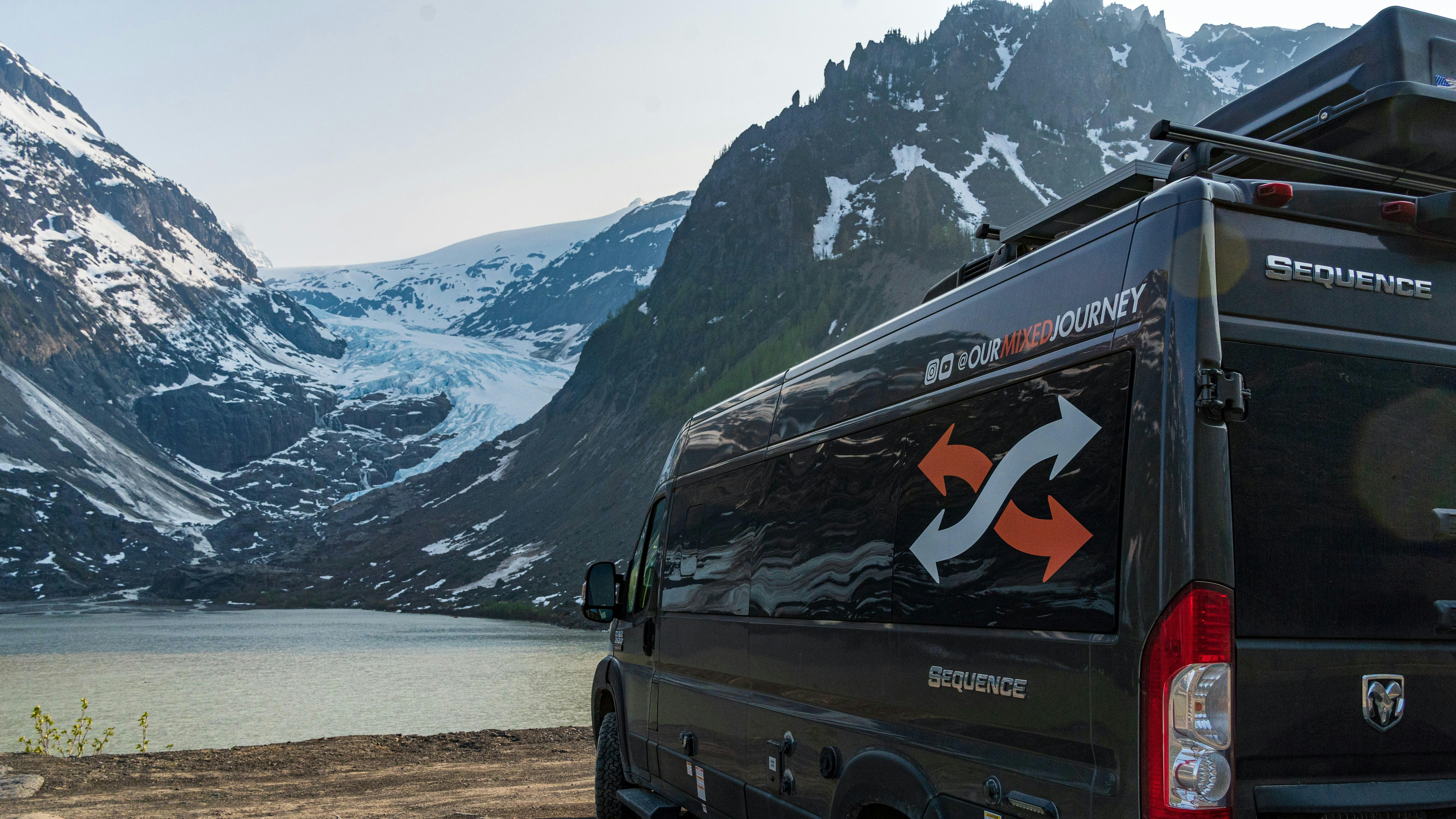 Gabe and Rocio Rivero's campervan parked in front of a lake with snowy mountains 