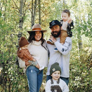 Autumn Bailey with her husband and three kids, posed for a picture amid green trees.