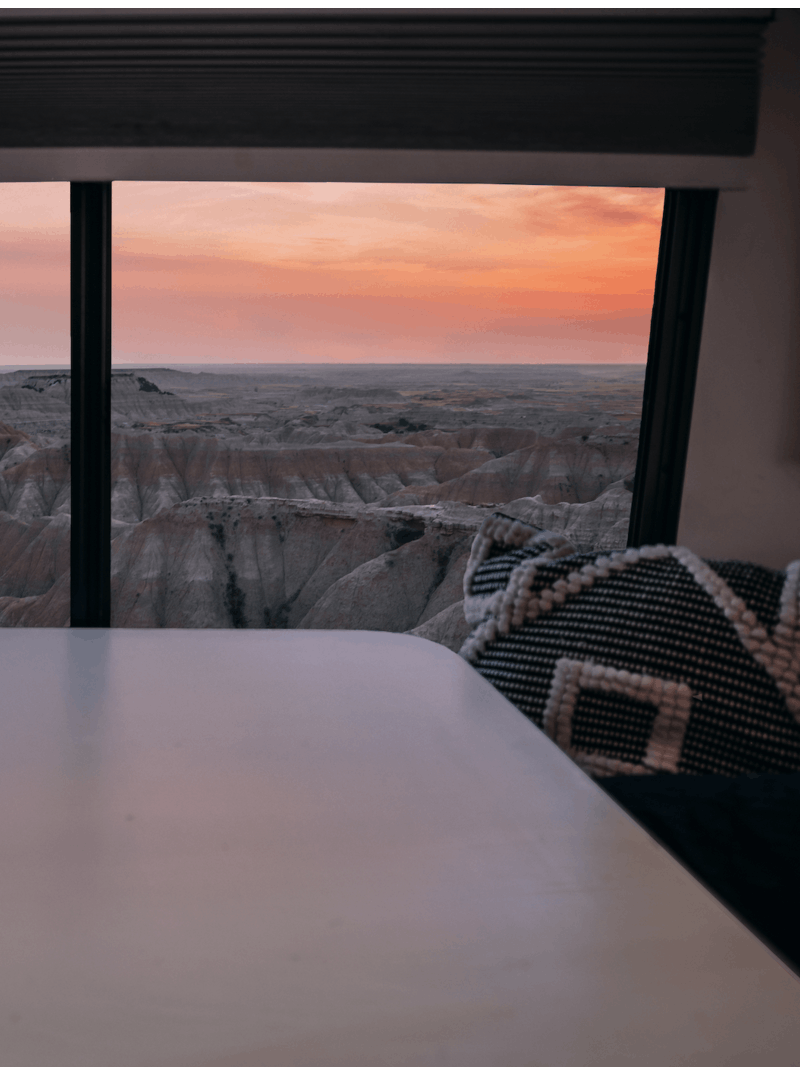 A sunset view out an RV window, facing the landscape of Badlands National Park.