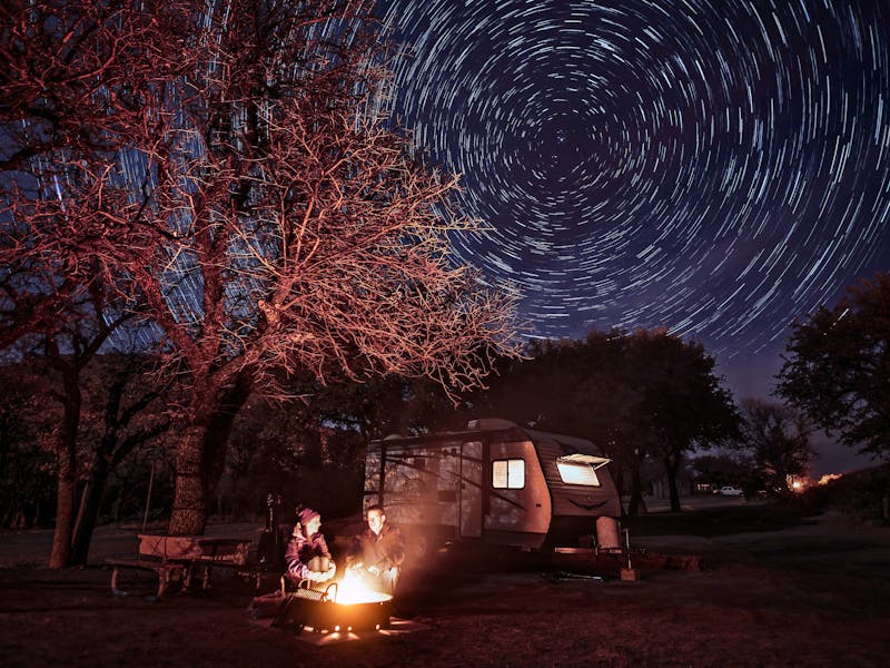 Alison Takacs and her husband around a campfire with a starry sky behind them.