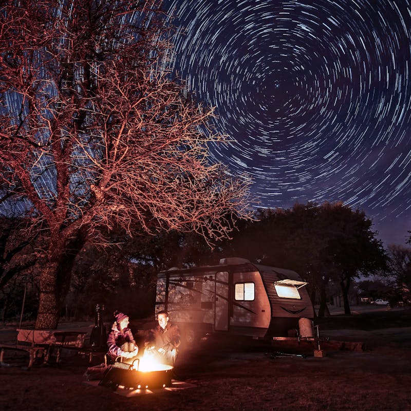 Alison Takacs and her husband around a campfire with a starry sky behind them.