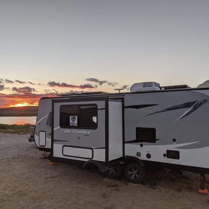 Ben and Christina McMillan's RV boondocking next to a lake at sunset