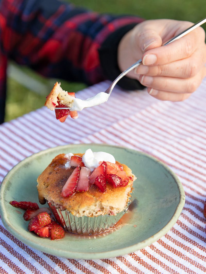 A uses a fork to scoop up a strawberry corn muffin.